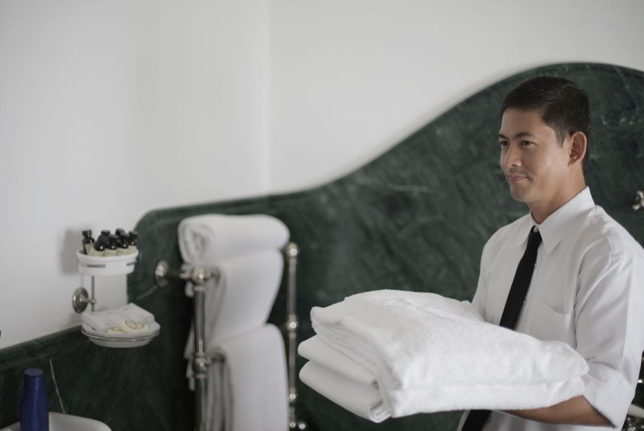 Three professional cleaners from Paddington Cleaners are engaged in surface cleaning and sanitisation within a modern living room. The room features a polished wooden floor, a fabric sofa, and a coffe